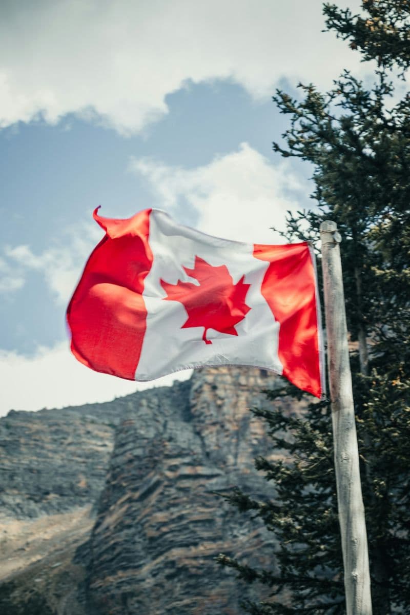 Canadian flag flying beside a rocky mountain cliff