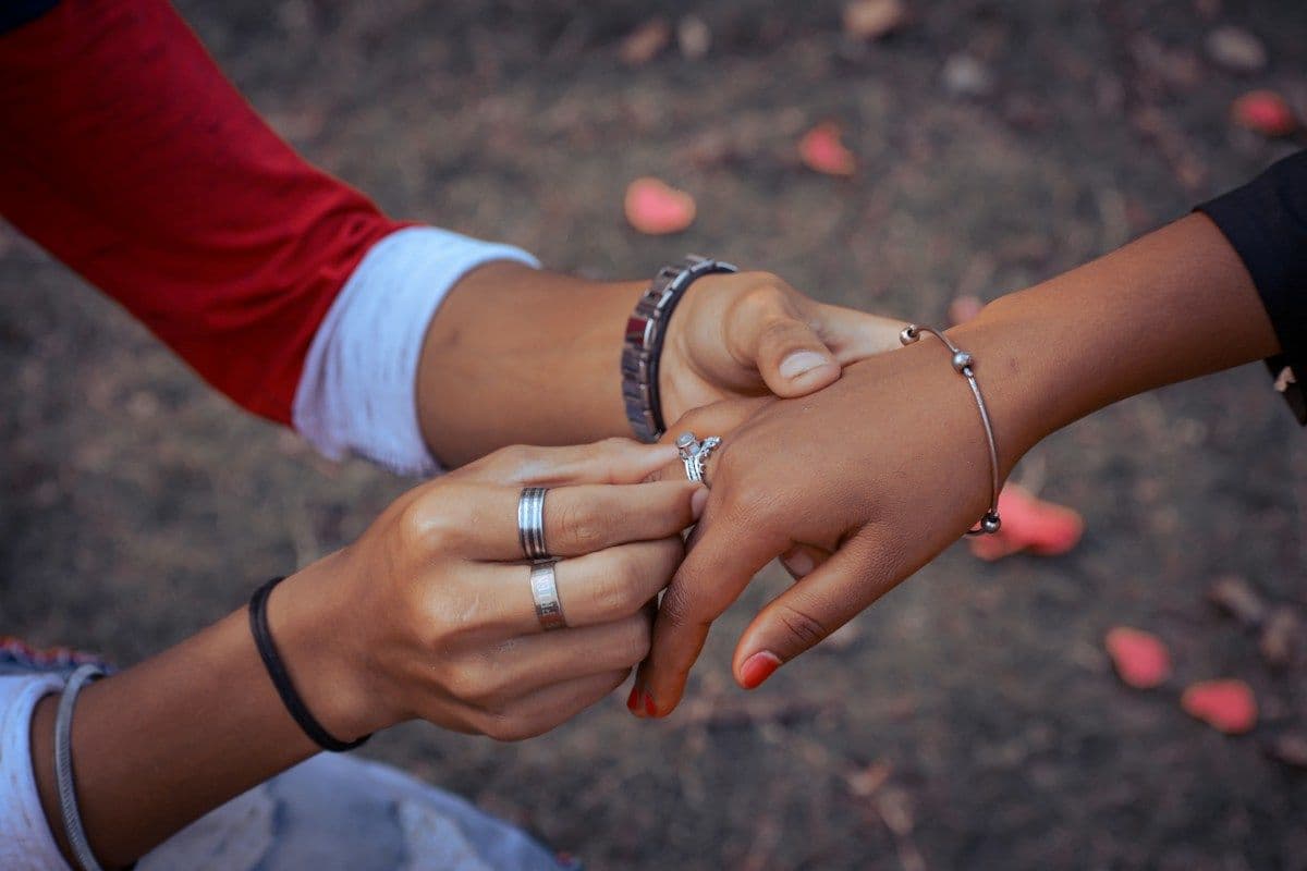 A couple holding hands as a ring is placed on a finger