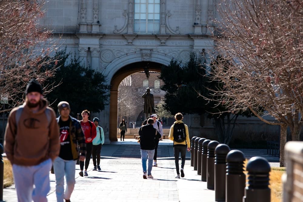 Students walking through the arched entrance of a university campus